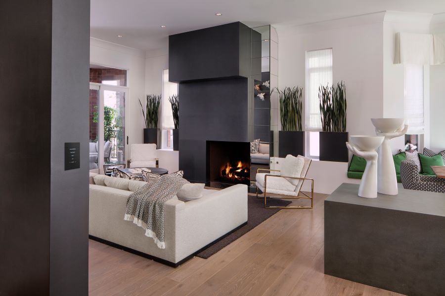 A modern home with a lit fireplace and an in-wall keypad to control a Crestron home.